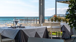 An outdoor dining area with tables set for two, overlooking a beach and the sea. - Anxur Village Camping (Fondi)