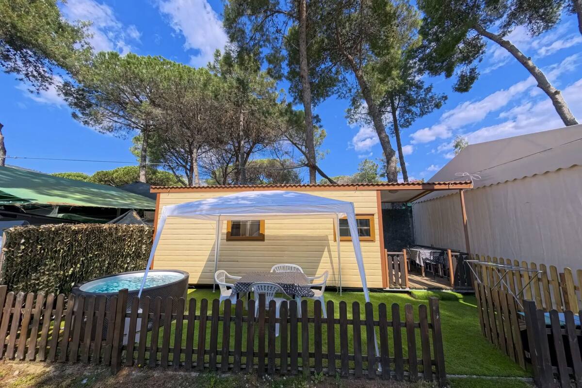 Eine kleine Holzhütte mit Whirlpool, umzäunter Terrassenbereich und Pool.