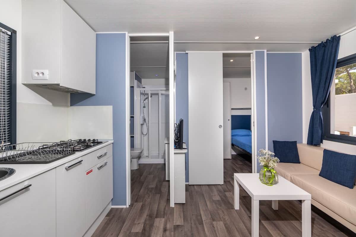 Ein kompakter, moderner Wohnraum mit einer Küchenzeile, einem Badezimmer und einer Sitzecke.