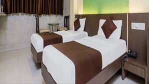 A hotel room with two beds, a small table, and a chair. - Panvel Palace (Panvel)