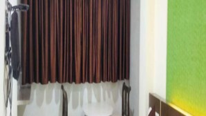 A hotel room with a bed, a small round table, two chairs, and a window with dark curtains. - Panvel Palace (Panvel)
