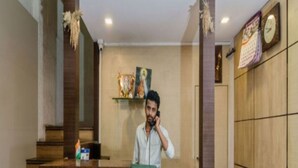 A reception desk with a person standing behind it, a clock on the wall, and a calendar. - Panvel Palace (Panvel)