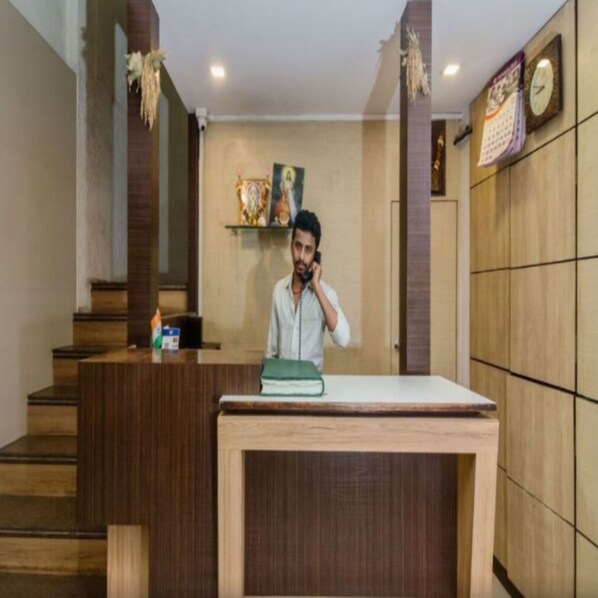 A reception desk with a person standing behind it, a clock on the wall, and a calendar.