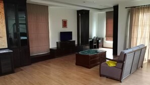 A spacious living room with a wooden floor, a sofa, a coffee table, and a TV. - Capital O 90653 Maxwell Inn Boutique Hotel (Taiping)