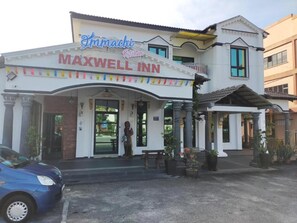 Experience the charm of the Maxwell Inn, a traditional hotel with a welcoming entrance and beautifully landscaped porch.