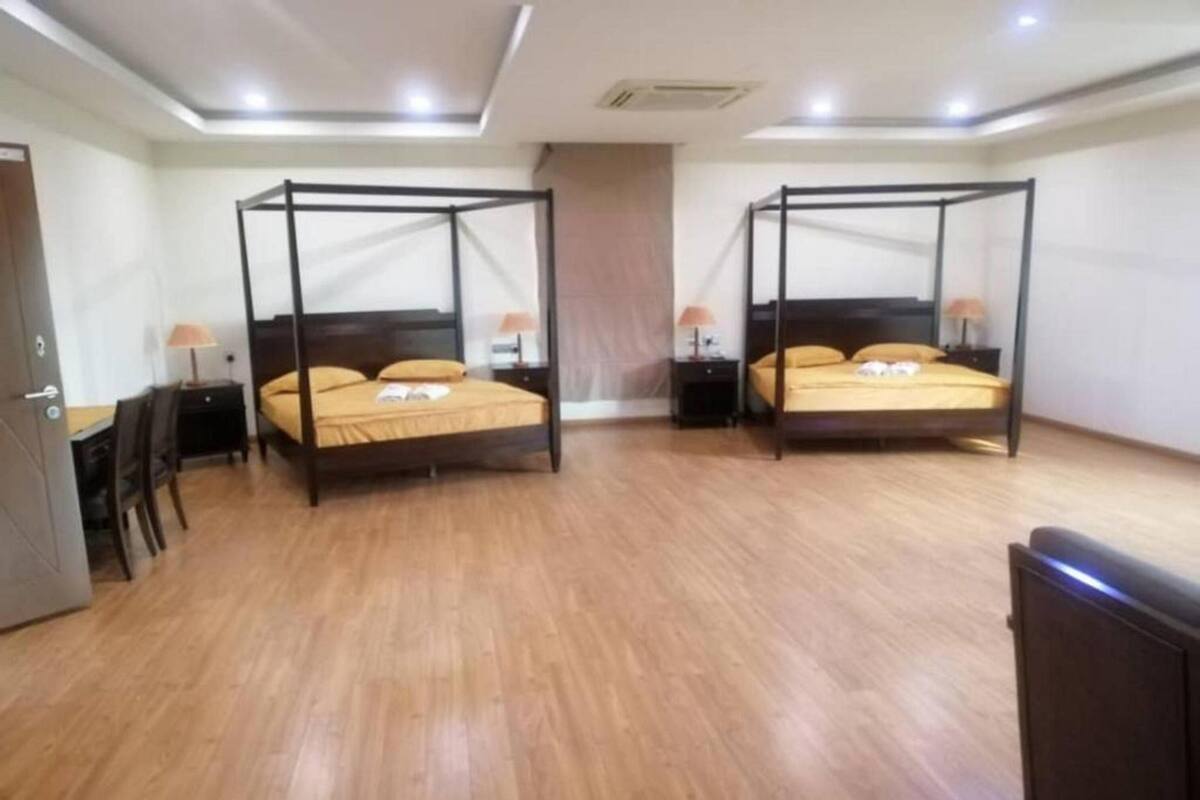 Une chambre dotée de deux lits à baldaquin, d’un plancher en bois et d’un bureau avec une chaise.