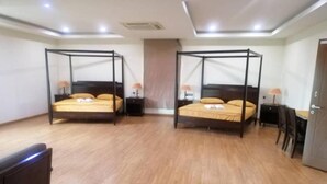 A hotel room with two four-poster beds, wooden flooring, and a desk with a chair. - Capital O 90653 Maxwell Inn Boutique Hotel (Taiping)