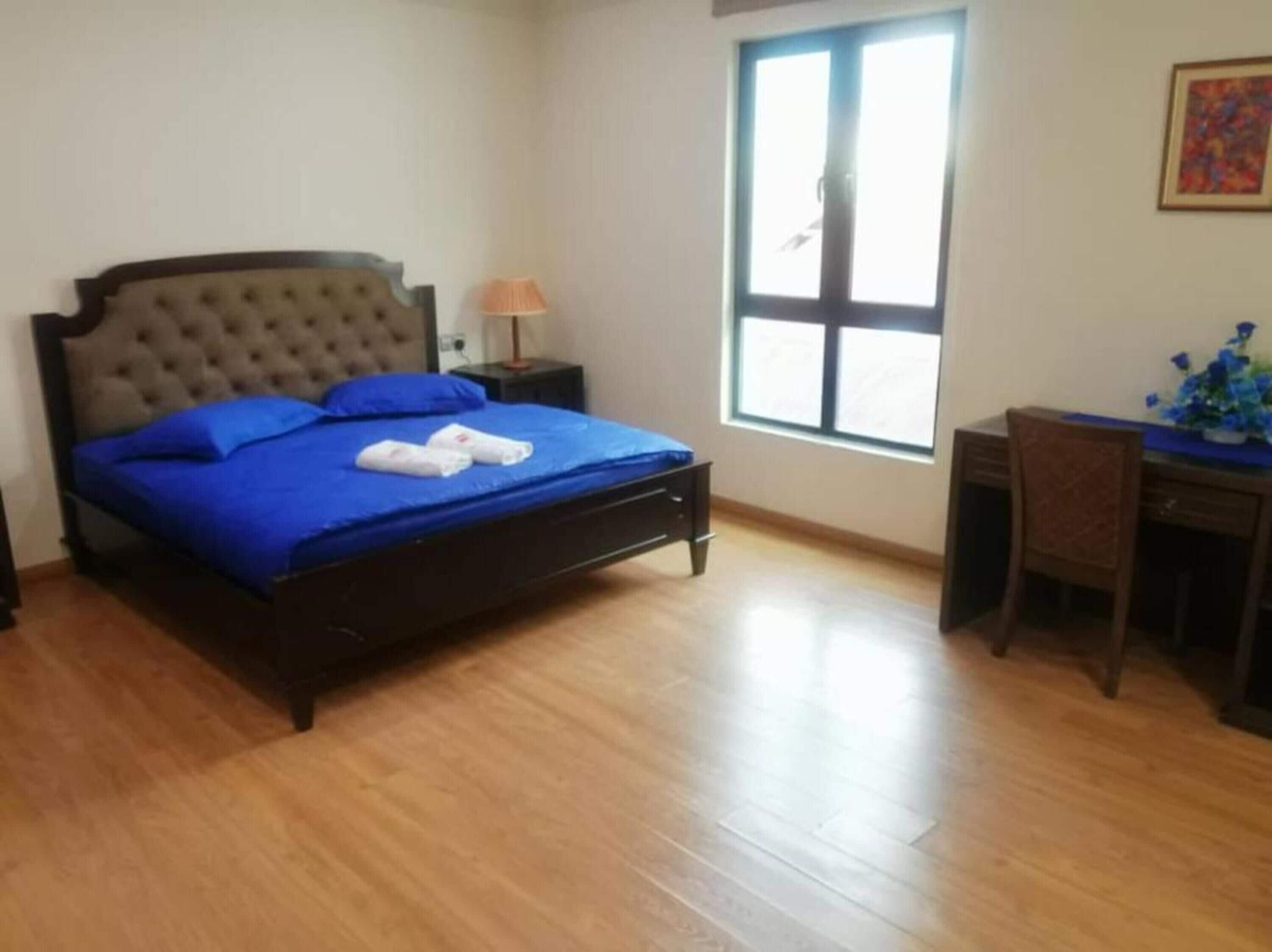 A bedroom with a bed, a desk, and a chair.
