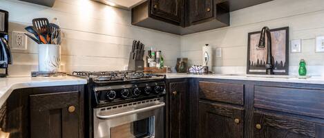 A kitchen with dark wood cabinets, a stainless steel stove, and a white countertop.