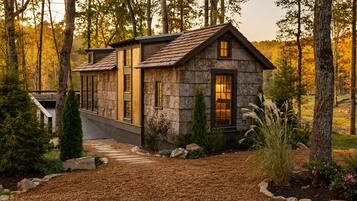Un chalet rustique avec une façade en pierre, une terrasse en bois et un jardin bien entretenu.