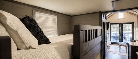 Une chambre à coucher de taille réduite, avec un lit superposé, une fenêtre avec des stores et une vue sur un patio extérieur.