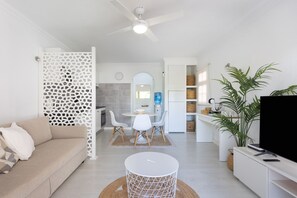 A modern living room with a sofa, a dining table with chairs, a TV, and a ceiling fan. - The White apartment in Amarilla Golf (San Miguel de Abona)