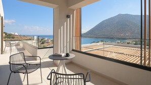 A balcony with two chairs, a small table, and a view of a mountain and sea. - Nandana Luxury Villa, an infinite blue experience (Rethymno)