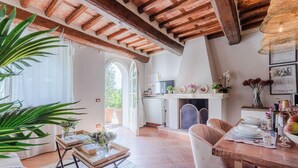 A spacious living area with a wooden ceiling, a dining table set for four, and a kitchen in the background.