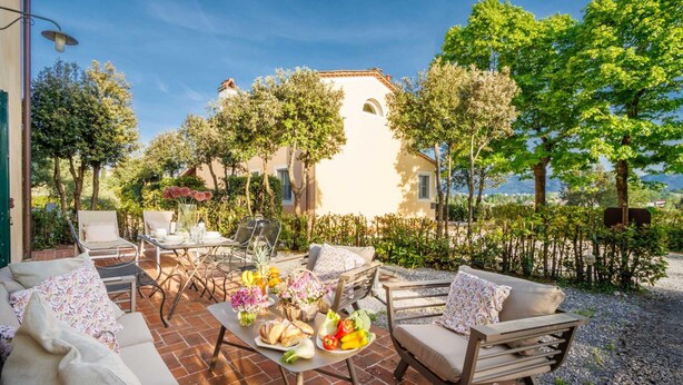 An outdoor patio with a dining table set with food, surrounded by seating.
