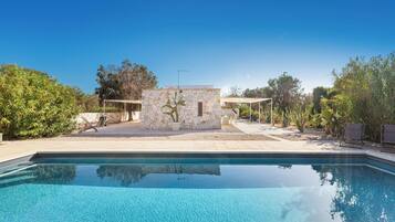 Une piscine avec un mur en pierre et un petit bâtiment en arrière-plan.
