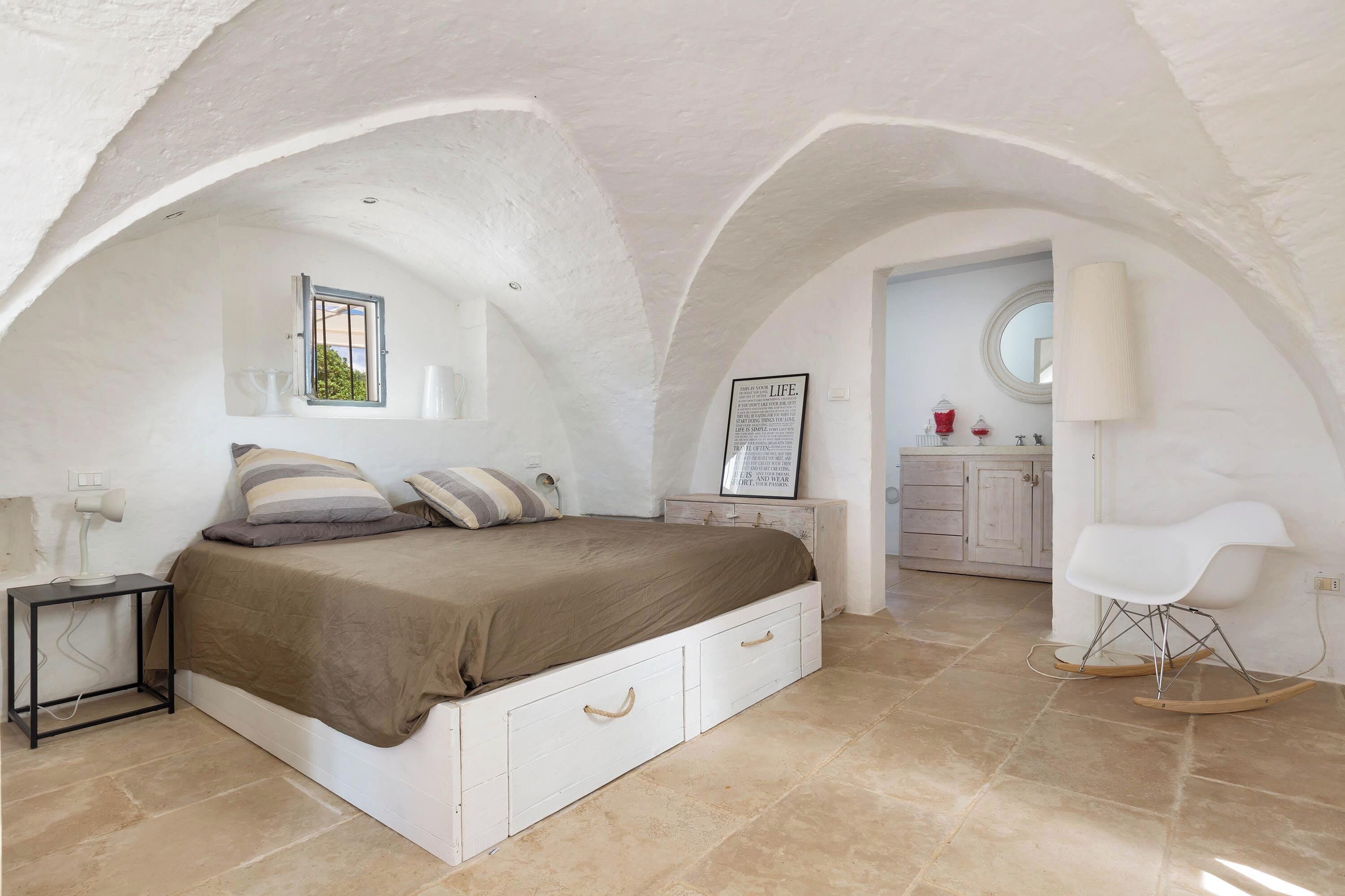 Une chambre à coucher avec un lit, une table de chevet et un fauteuil à bascule.