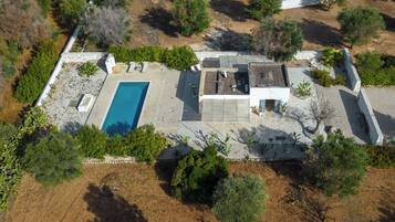 Vue aérienne d’une propriété dotée d’une piscine, d’un espace patio et d’une végétation luxuriante.