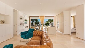 Una sala de estar moderna con un sofá de cuero, sillas color turquesa y un comedor con vistas.
