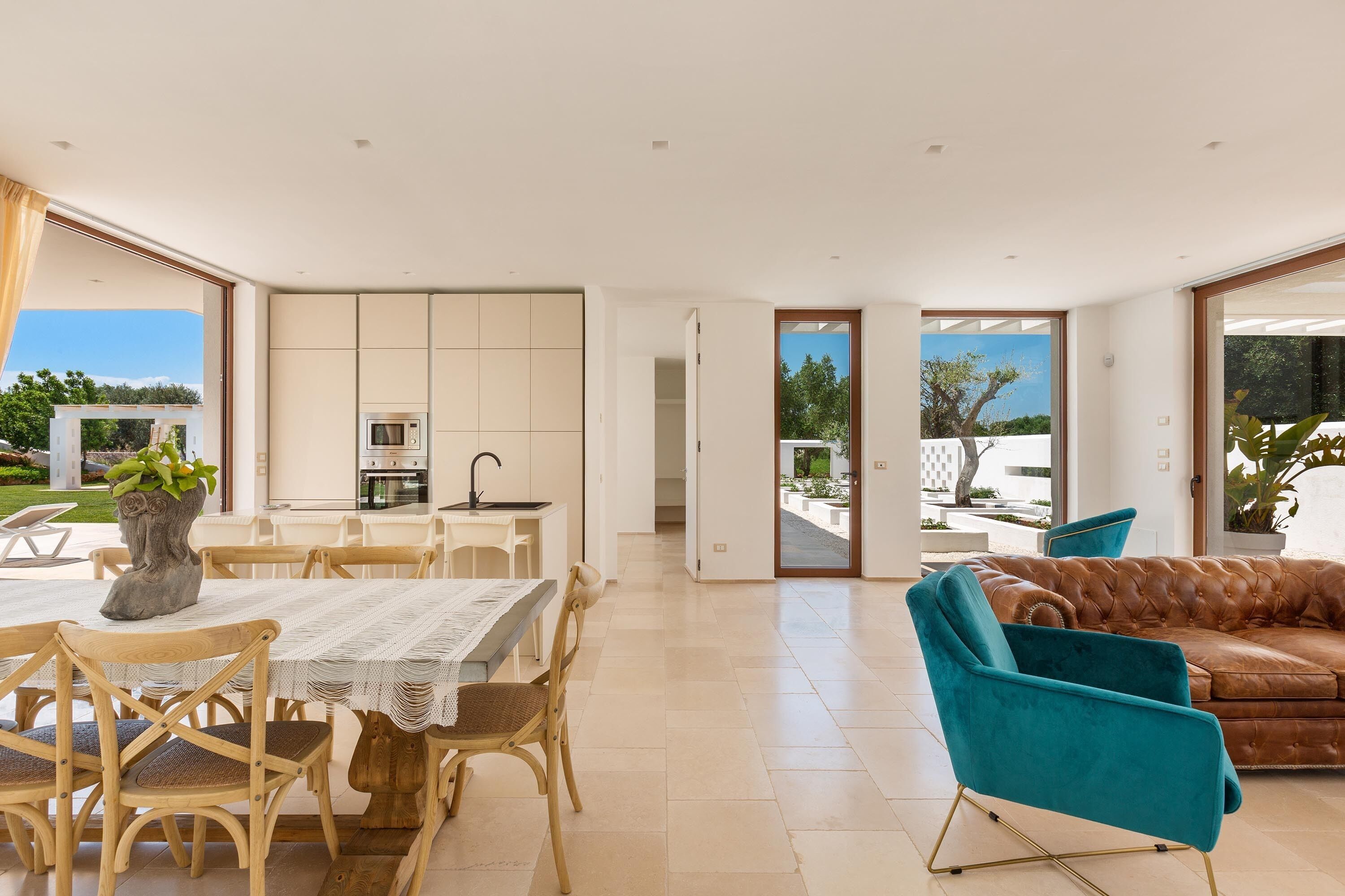 A spacious living area with a dining table, chairs, a sofa, and a kitchen area.