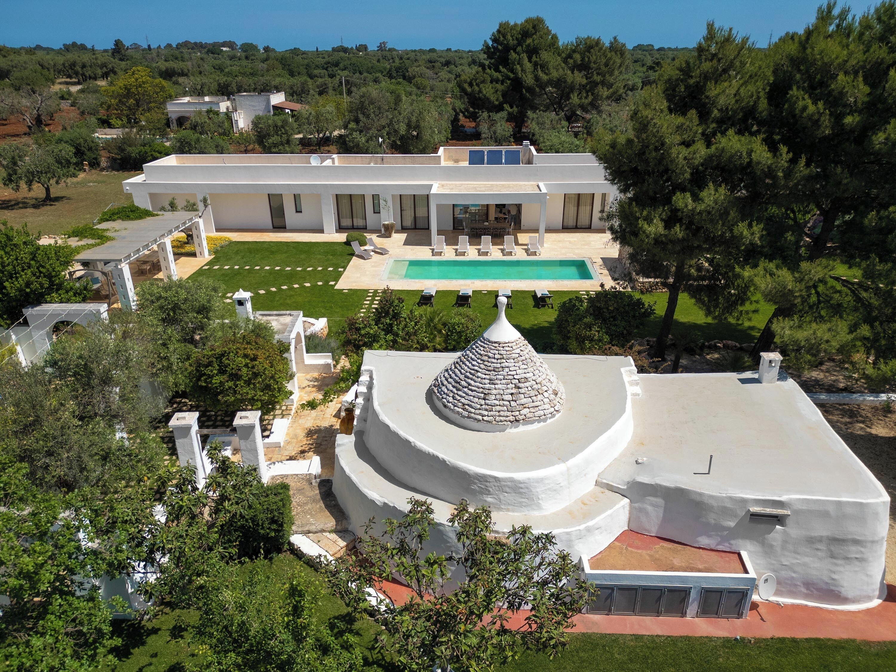Una villa moderna con piscina, una estructura en forma de cúpula y un jardín bien cuidado.