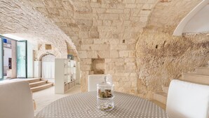 A room with a stone wall, a round table with a star-patterned tablecloth, and a glass jar with items on it. - 2774 Casa Chianchizze by Barbarhouse (Ceglie Messapica)