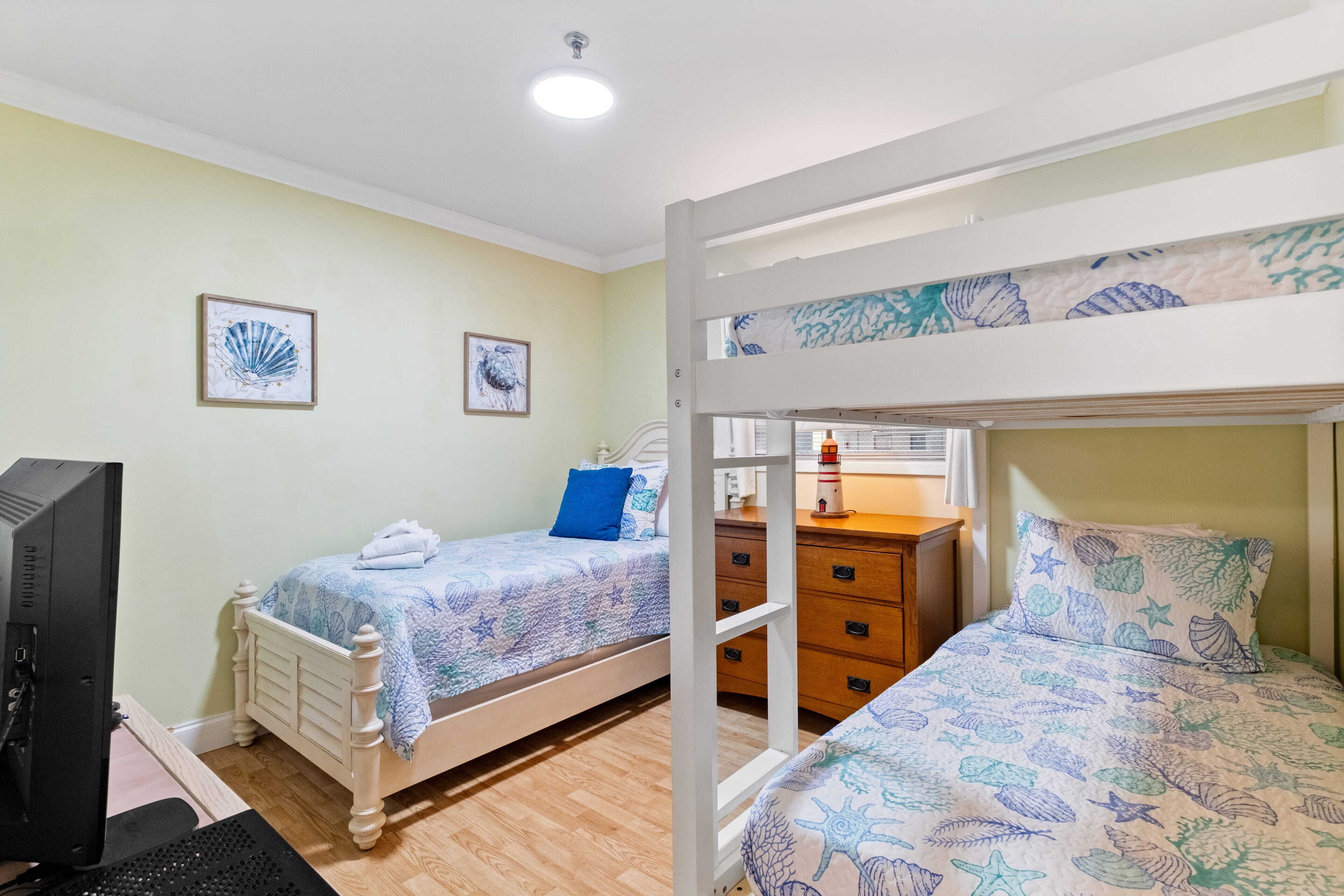 A room with bunk beds, a desk with a computer, and a dresser.