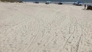 Una playa arenosa con huellas e identificadas algunas sombrillas.
