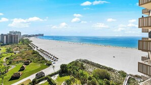 Et hotel ved stranden med udsigt til havet, en sandstrand og en parkeringsplads.