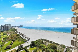 Un hotel sulla spiaggia con vista sull'oceano, una spiaggia sabbiosa e un'area parcheggio.