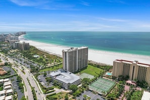 Un hotel sulla spiaggia con campo da tennis, parcheggio e vista sull'oceano.