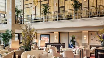 A spacious lobby with a high ceiling, large windows, and a second-floor balcony.