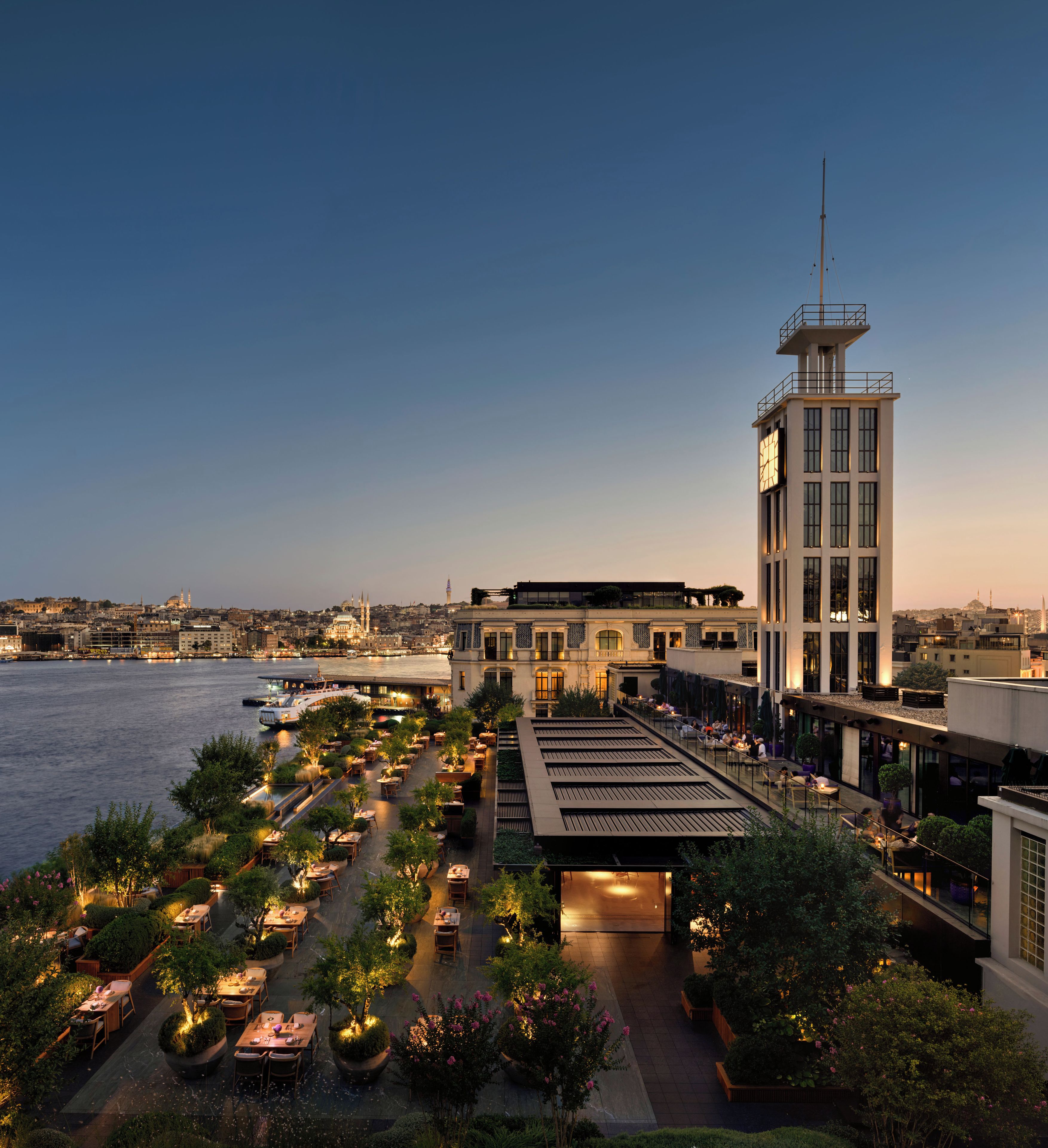 A rooftop terrace with outdoor seating, a clock tower, and a view of the cityscape.