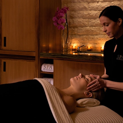 A spa setting with wooden cabinets, a stone wall, and a sign reading "SPA THE PENINSULA".