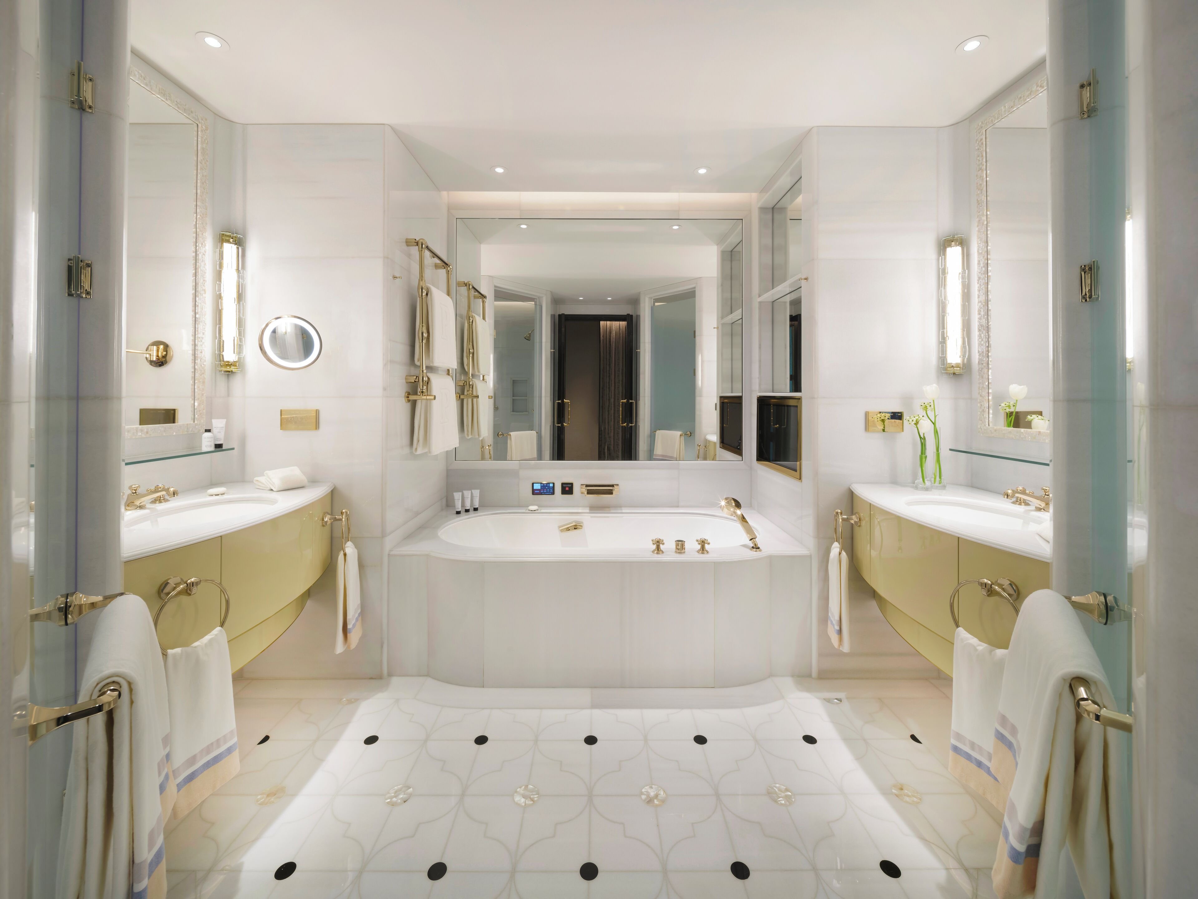 Une salle de bain moderne avec deux lavabos, une grande baignoire et un miroir au-dessus de la baignoire.