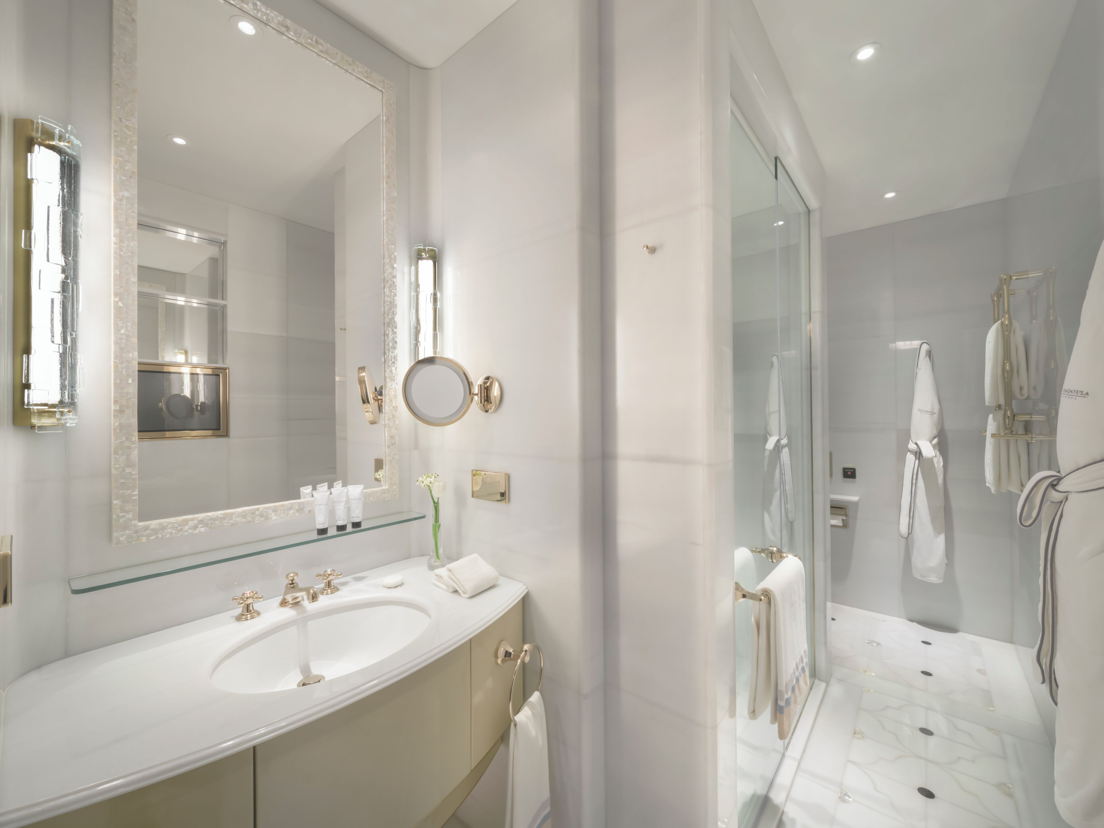 Un baño moderno con un espejo grande, un lavabo y una zona de ducha con mampara de vidrio.