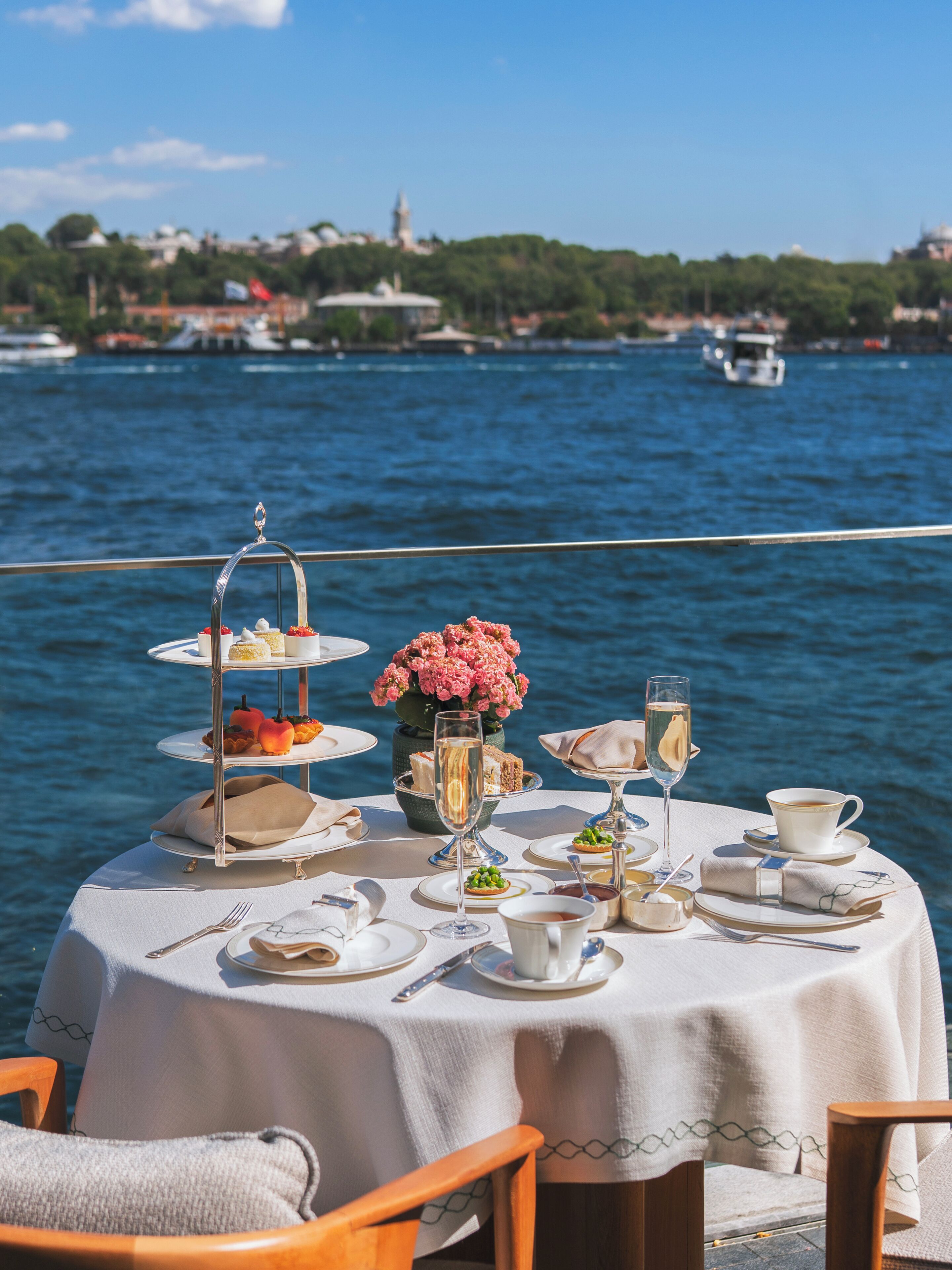 A table set for a meal with a view of the water and distant buildings.