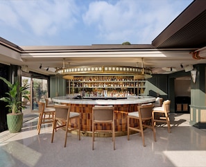 A bar area with a circular bar, multiple seating options, and a variety of bottles on shelves.