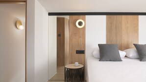 A modern hotel room with a bed, bedside table, and two wall-mounted lights. - Mayana Luxury Villa, an infinite blue experience (Rethymno)