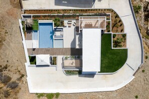 An aerial view of a modern house with a swimming pool, outdoor seating, and a landscaped garden. - Mayana Luxury Villa, an infinite blue experience (Rethymno)