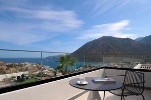 A balcony with a table, a chair, a book, and a view of the sea and mountains. - Mayana Luxury Villa, an infinite blue experience (Rethymno)