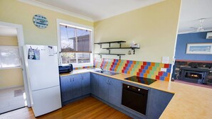 A compact kitchen with a built-in dishwasher, a toaster, and a colorful backsplash. - Kalimna Holiday House: Relax and enjoy the magnificent 180-degree water views (Kalimna)