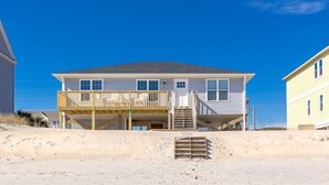 Une maison de plage à deux étages, dotée d’un balcon et d’une véranda couverte.