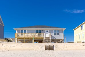 A two-story beach house with a balcony and a covered porch.