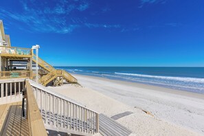 A wooden boardwalk leading to a beach with a clear sky.