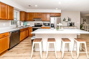 Una cocina moderna con armarios de madera, electrodomésticos de acero inoxidable y una isla central con taburetes de bar.