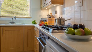 Una cocina moderna con armarios de madera, una estufa de acero inoxidable y un bol de manzanas en la encimera.