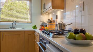 A modern kitchen with wooden cabinets, a stainless steel stove, and a bowl of apples on the counter.