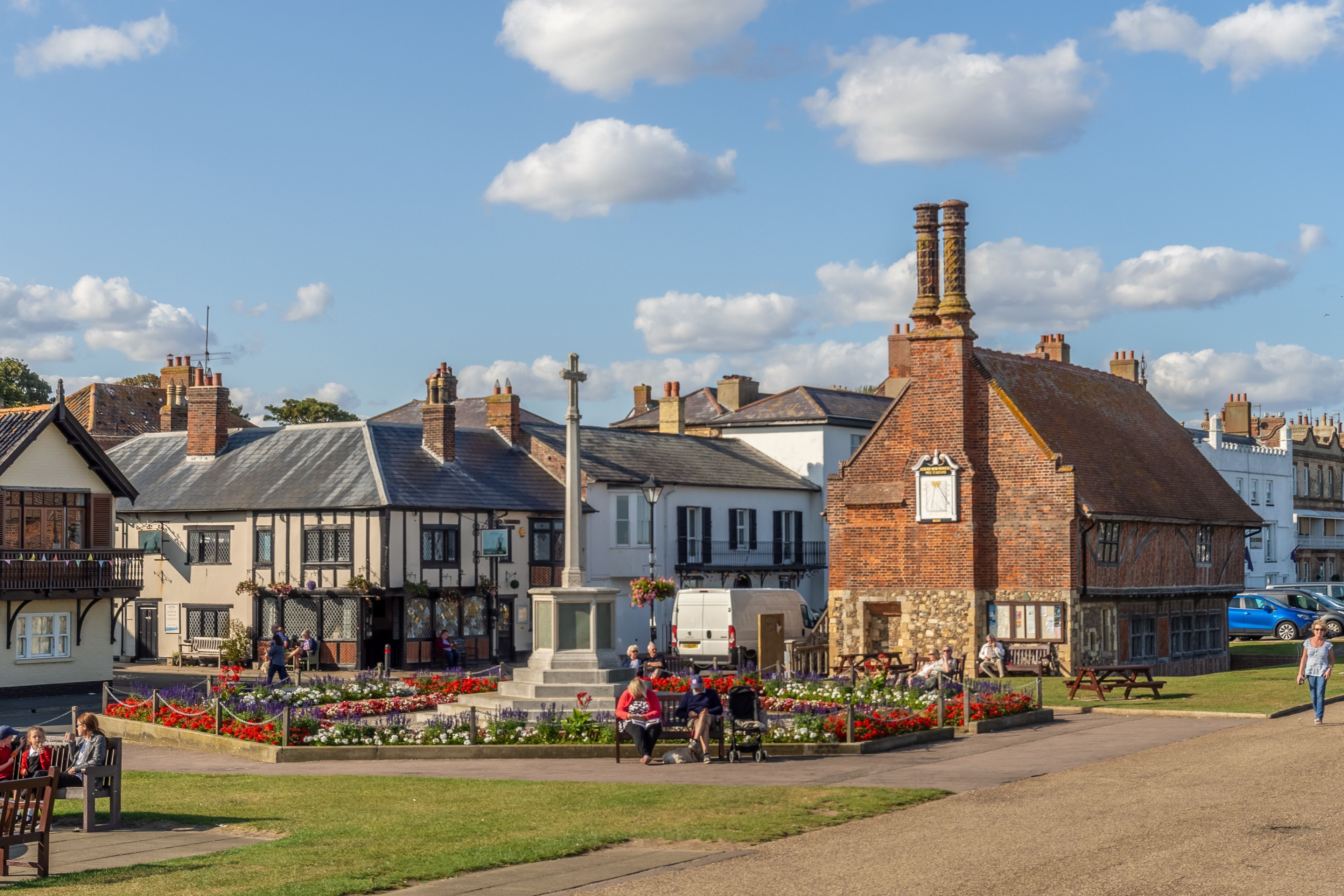A town square with a central monument, surrounded by traditional buildings and a flower garden.