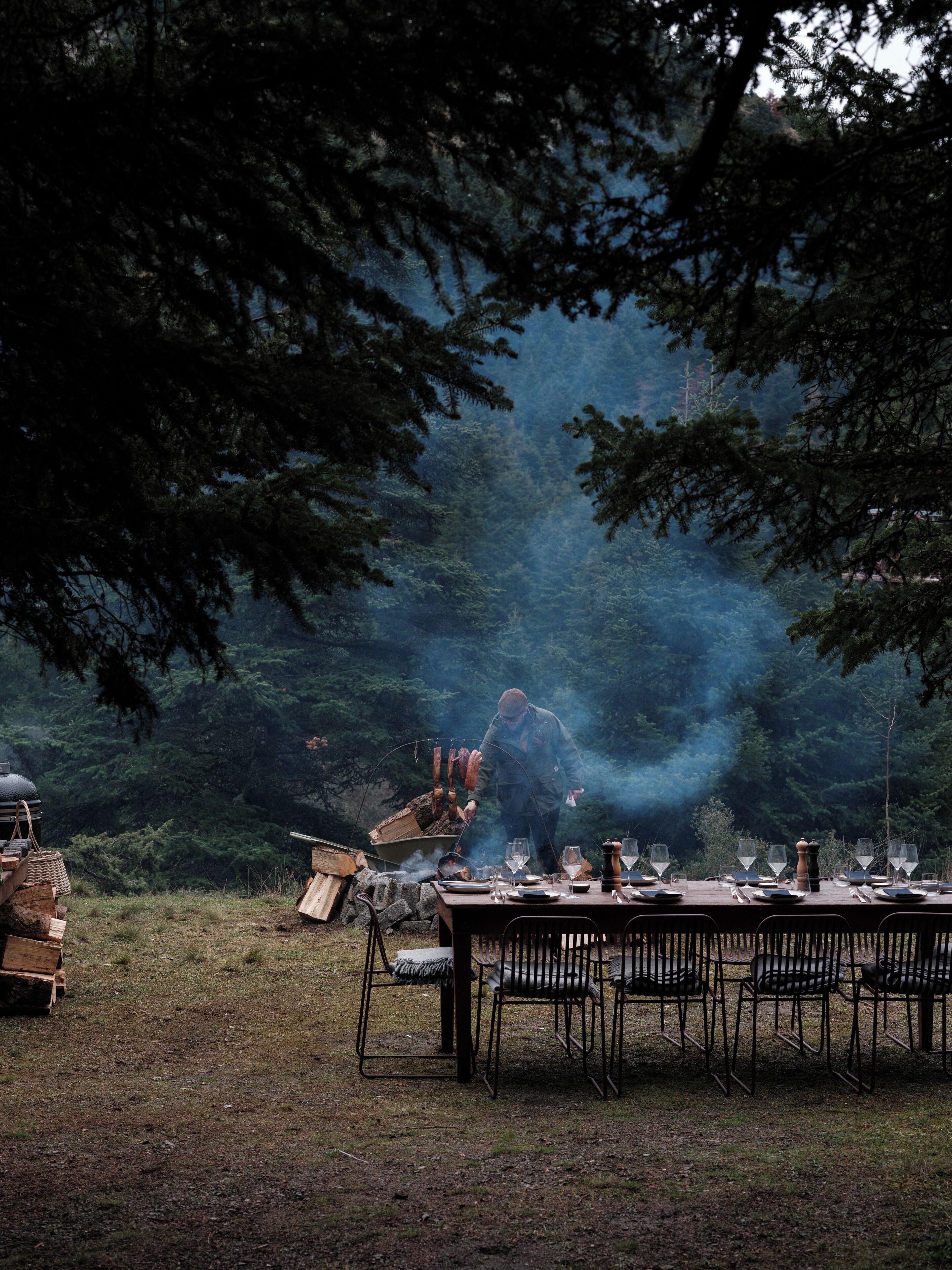 An outdoor dining setup with a table and chairs, surrounded by trees.
